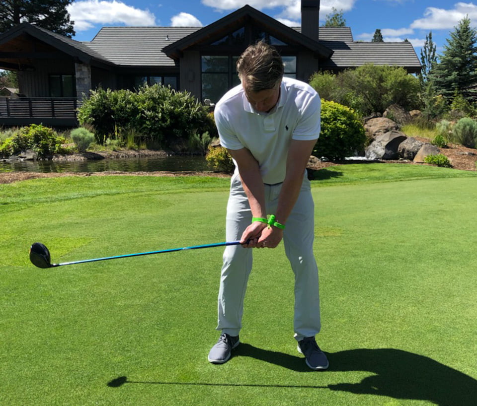 Golfer wearing WristBit Golf Band, teeing up